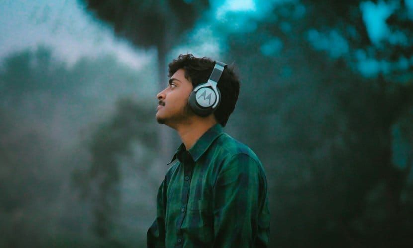 Man wearing headphones while listening to an audiobook on his phone