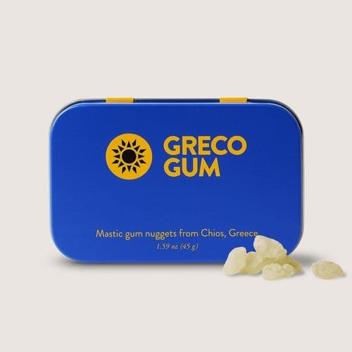 Blue tin of Greco Gum mastic gum nuggets on a light gray background