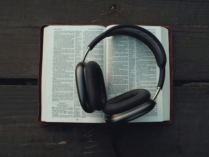 Wireless headphones resting on an open book, symbolizing audiobook listening