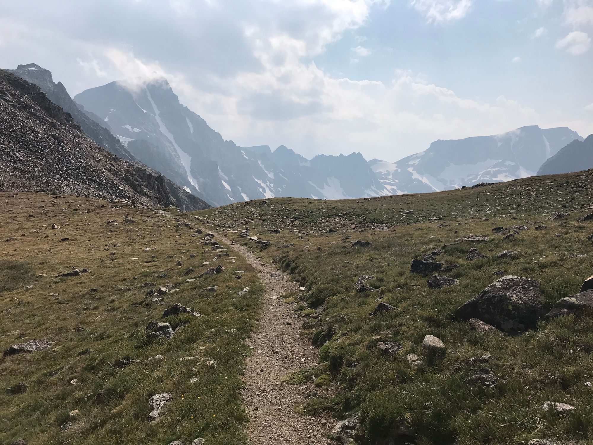 A path surrounded by high mountains and rocky green grass