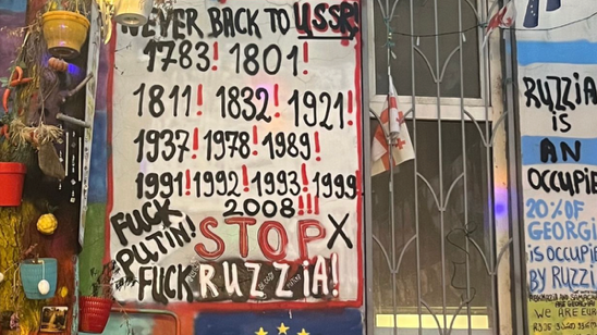 A wall with signs and graffiti

AI-generated content may be incorrect.