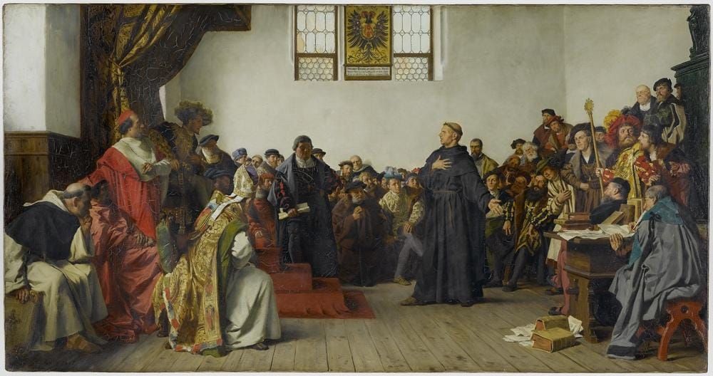 Gemälde mit vielen Personen zeigt. Im Zentrum steht Martin Luther in schwarzer Robe und argumentierend. Links sitzt im Schatten auf einem Podest der Kaiser, neben ihm römische Gesandte.