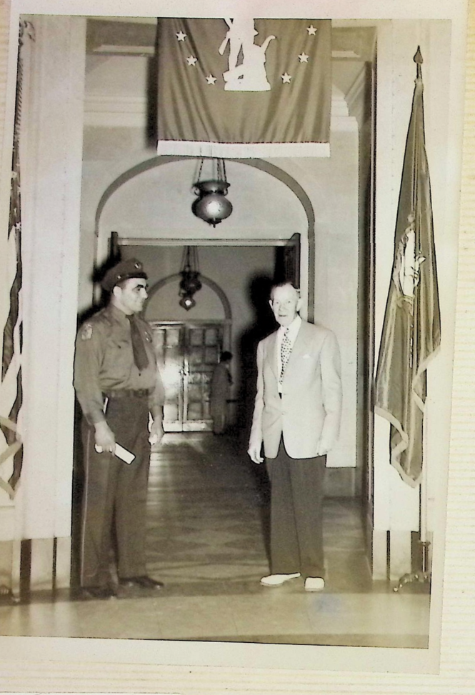 Officer Bull Curry in uniform standing with an official in a marble courthouse hall with flags
