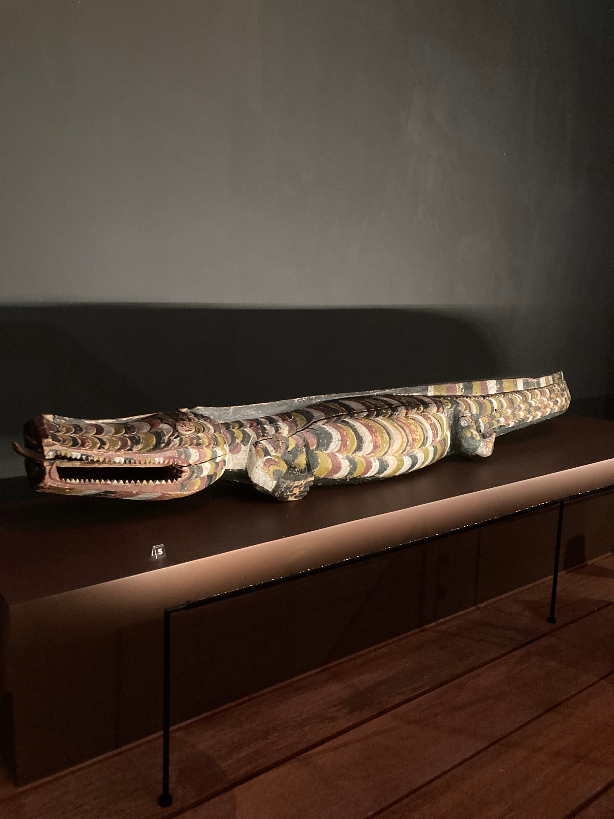 A crocodile carved from wood and painted in shades of black, white, yellow, and ochre.