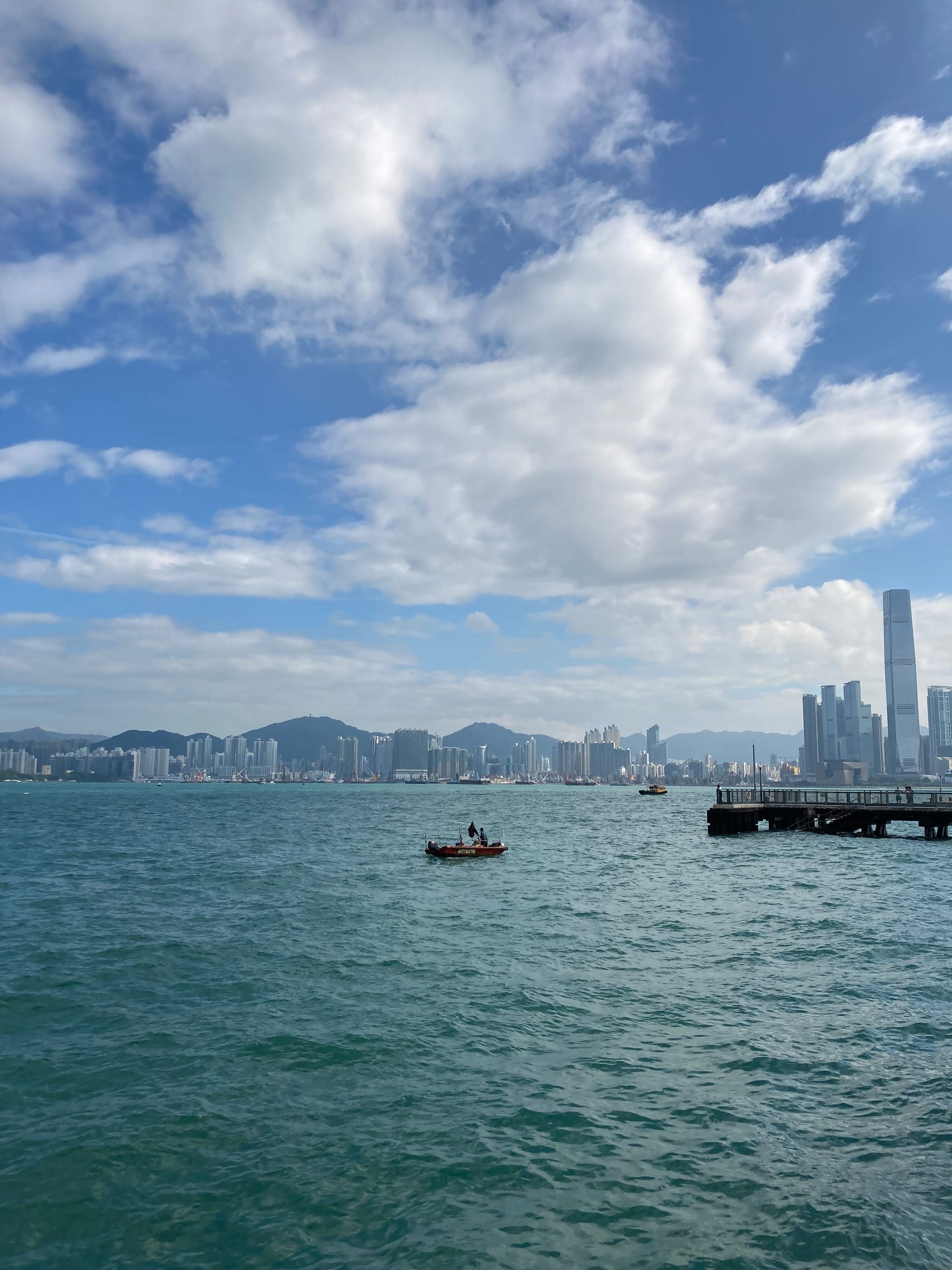 A small fishing boat in HK harbour with a view of Kowloon behind it.