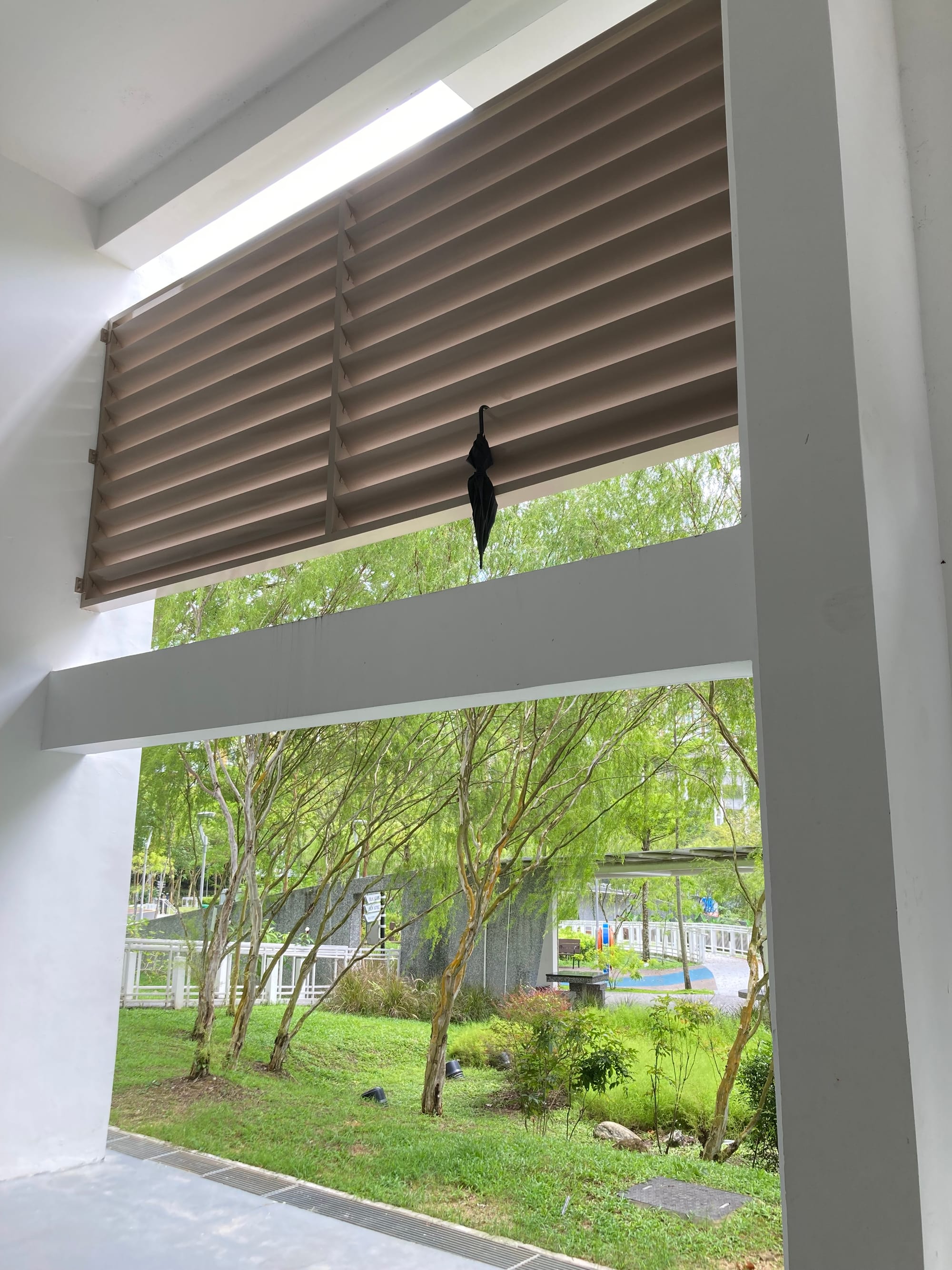 A black umbrella hangs off some louvred panels roughly 10 feet off the ground