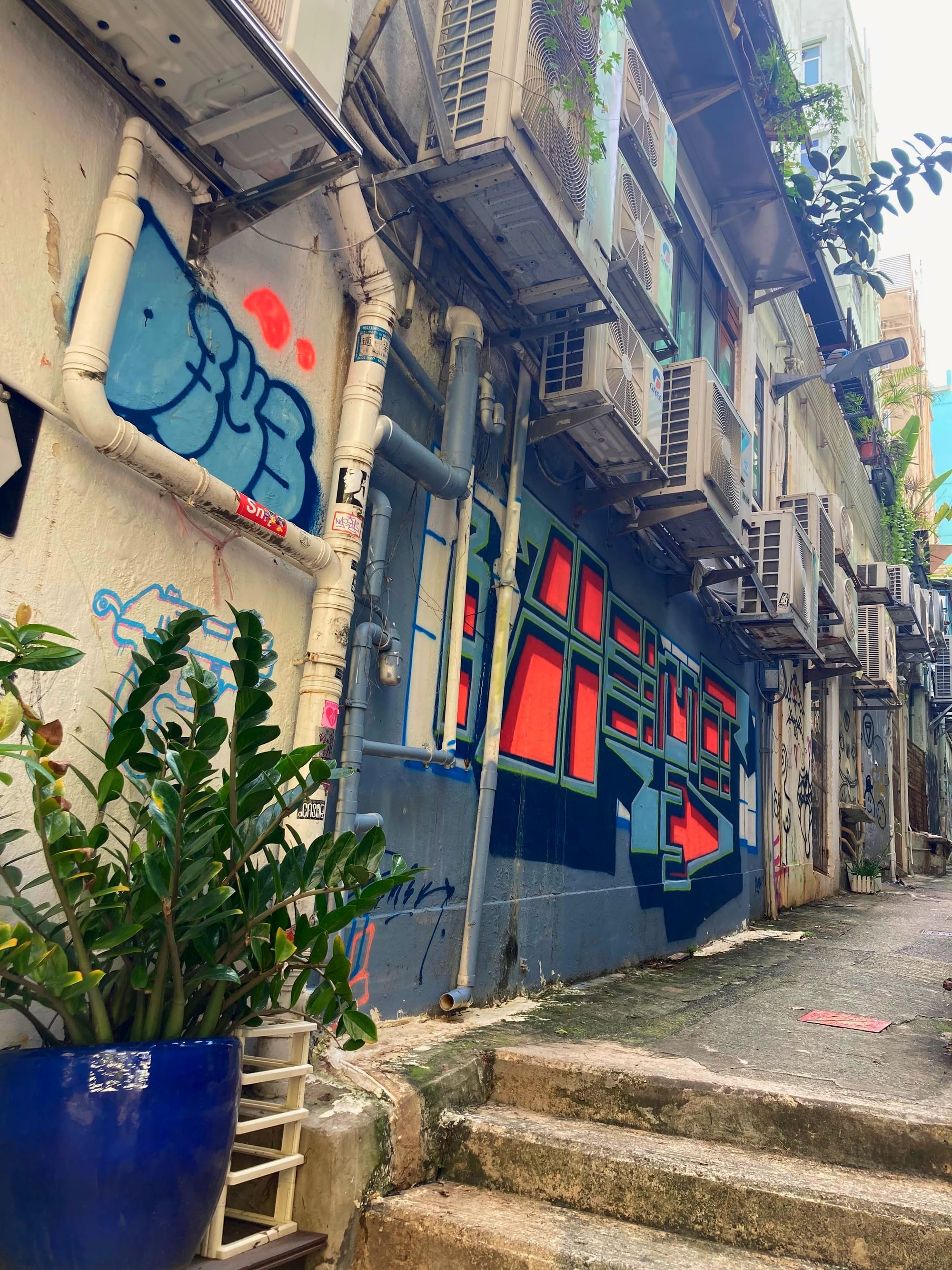 An alleyway with graffiti and air con units