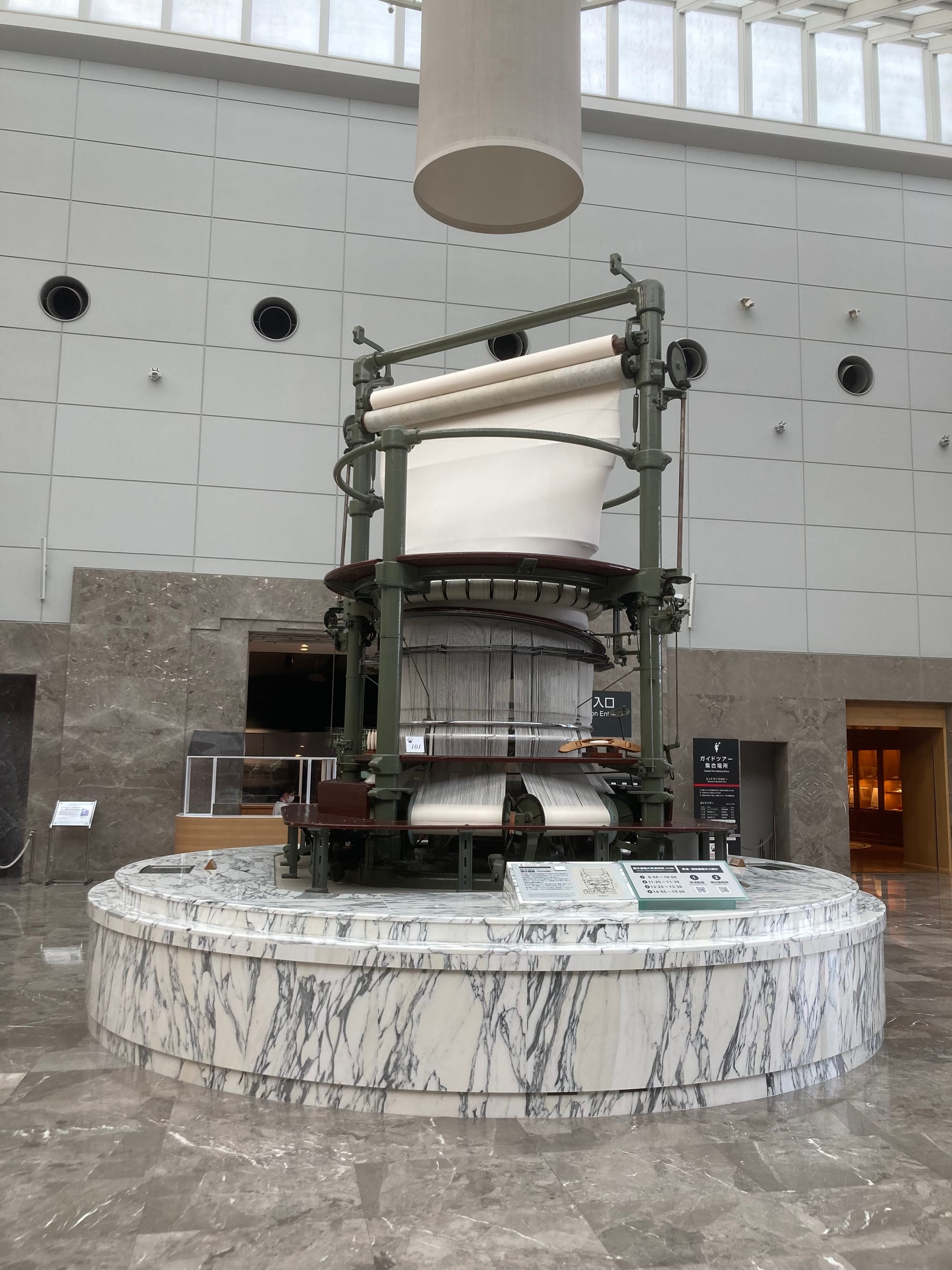 On a marble plinth stands a massive industrial circular loom.