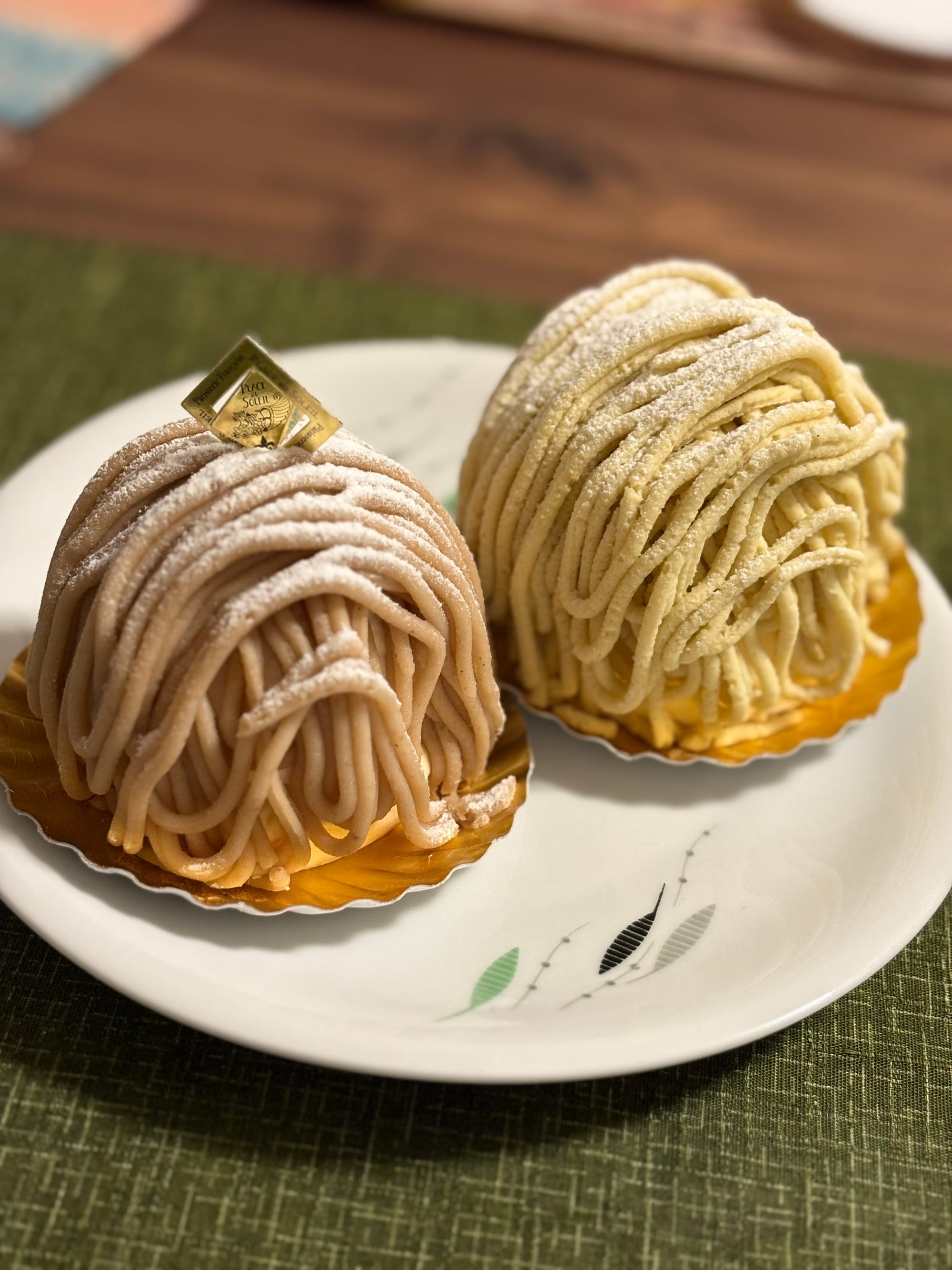 Two types of Mont Blancs, one darker and one paler, sit on a white plate.