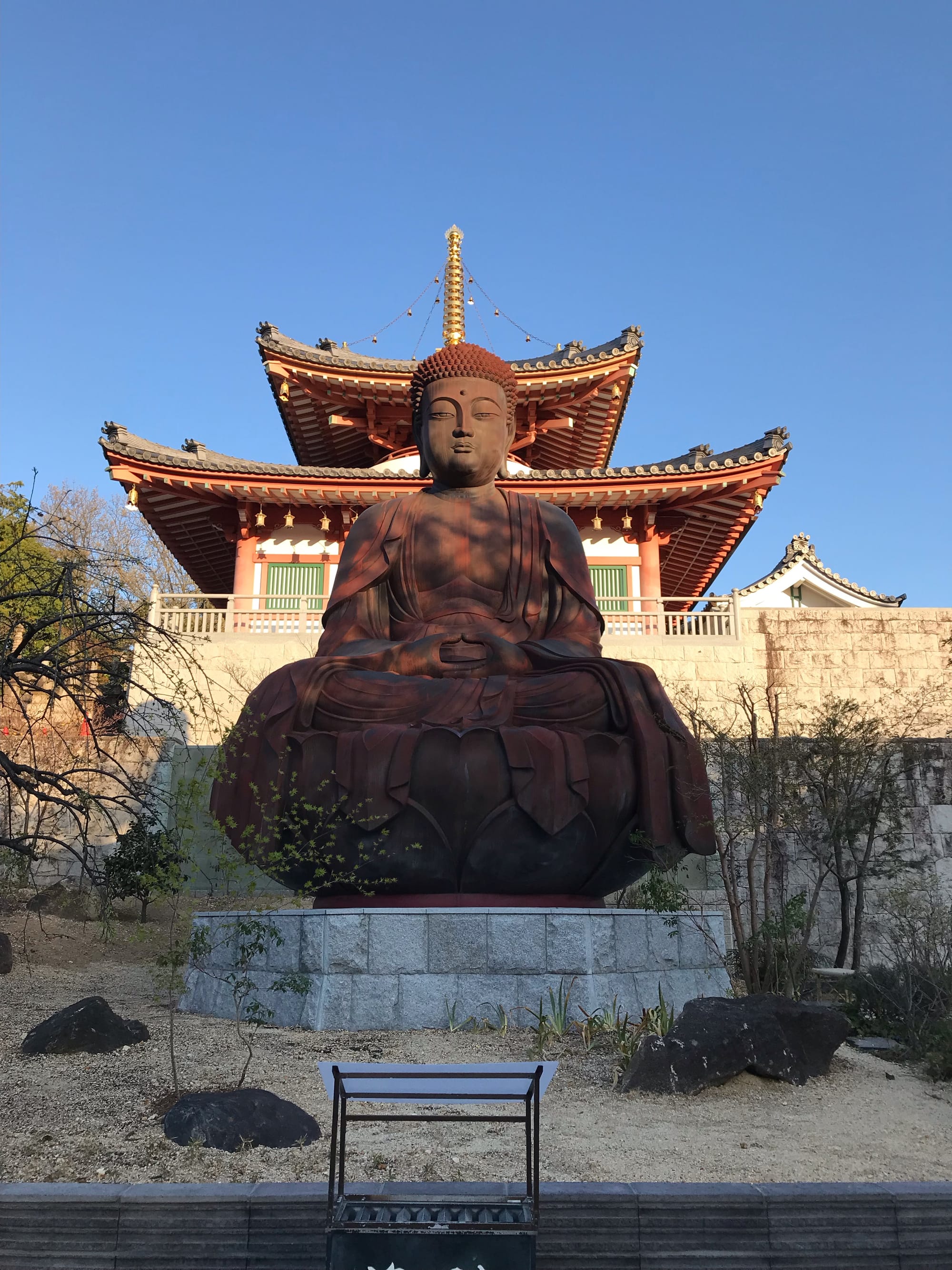 A lacquered bronze statue of a giant Buddha, or Daibutsu, in red tones.