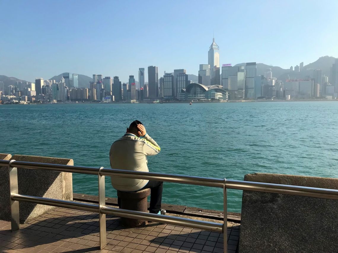A man rubs his head as he gazes at HK Island from Kowloon