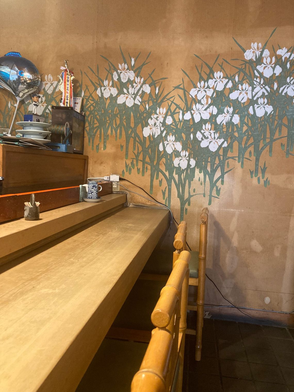 A sushi counter leads to a wall painting of white irises