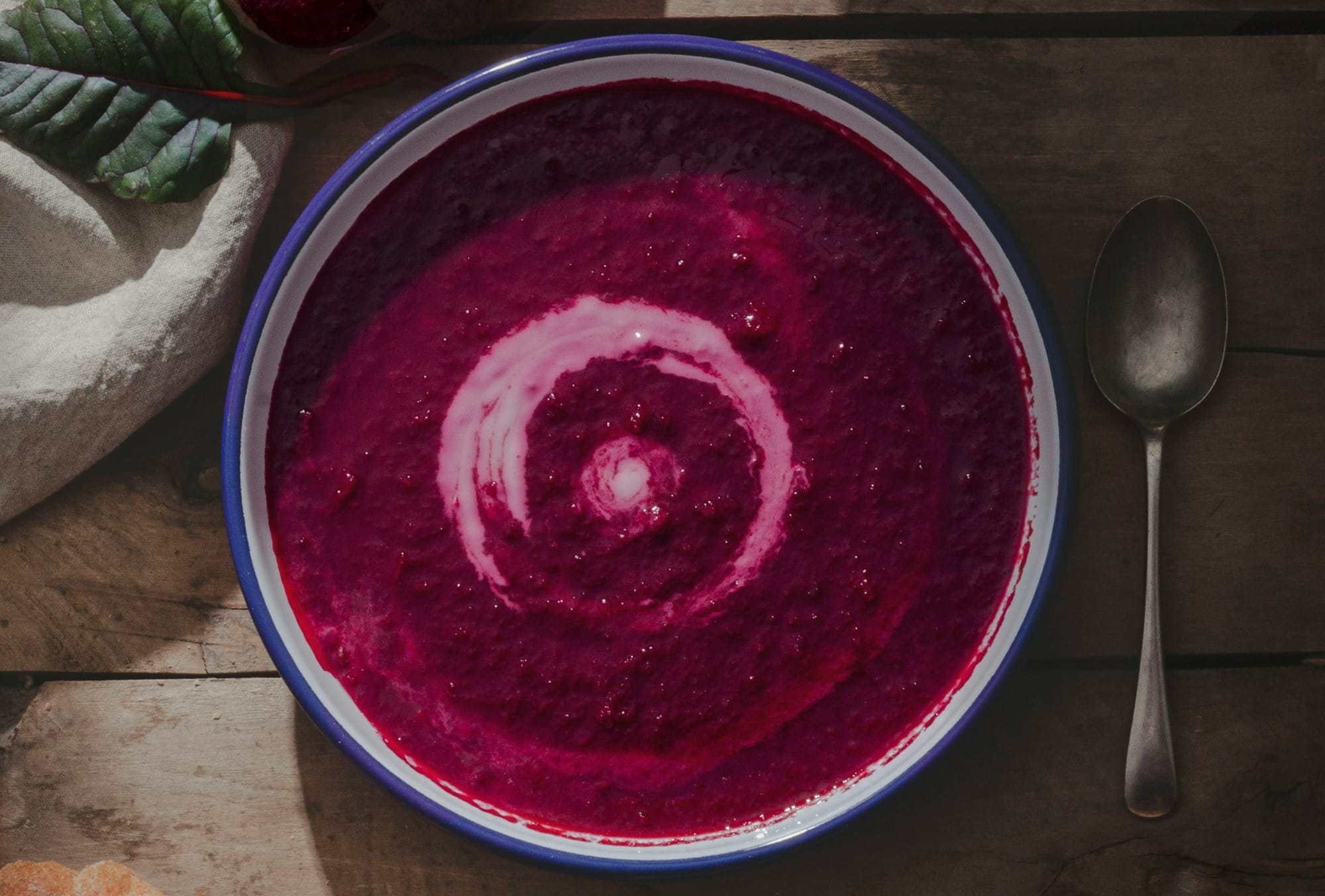 a bowl of beet soup on a wooden table