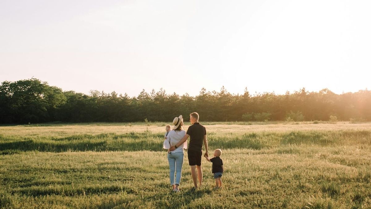 a family of mother and father in a field with 2 kids