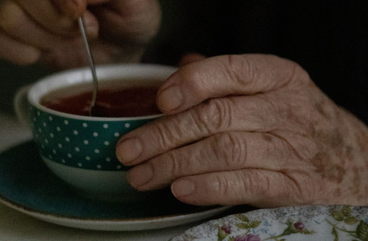 old hands holding a cup of tea