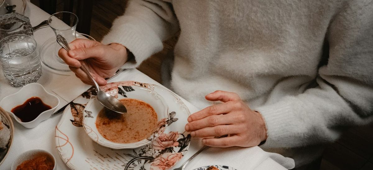 a person at the table eating soup