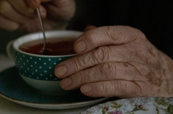 old hands holding a cup of tea