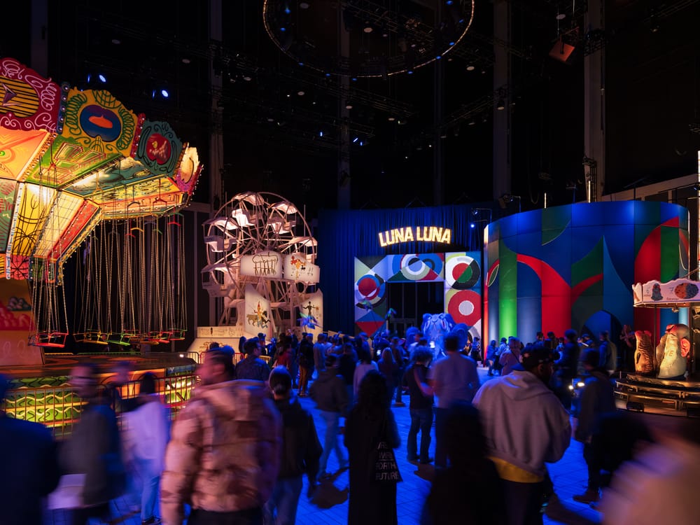 Crowds stand in front of amusement park ride art installations at Luna Luna in NYC