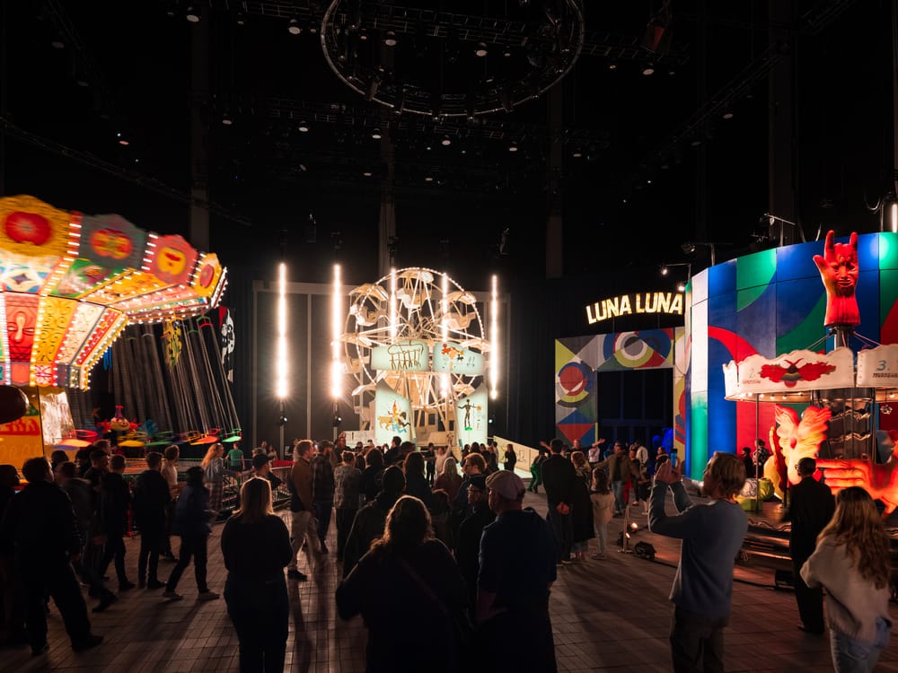 Crowds stand in front of amusement park ride art installations at Luna Luna in NYC