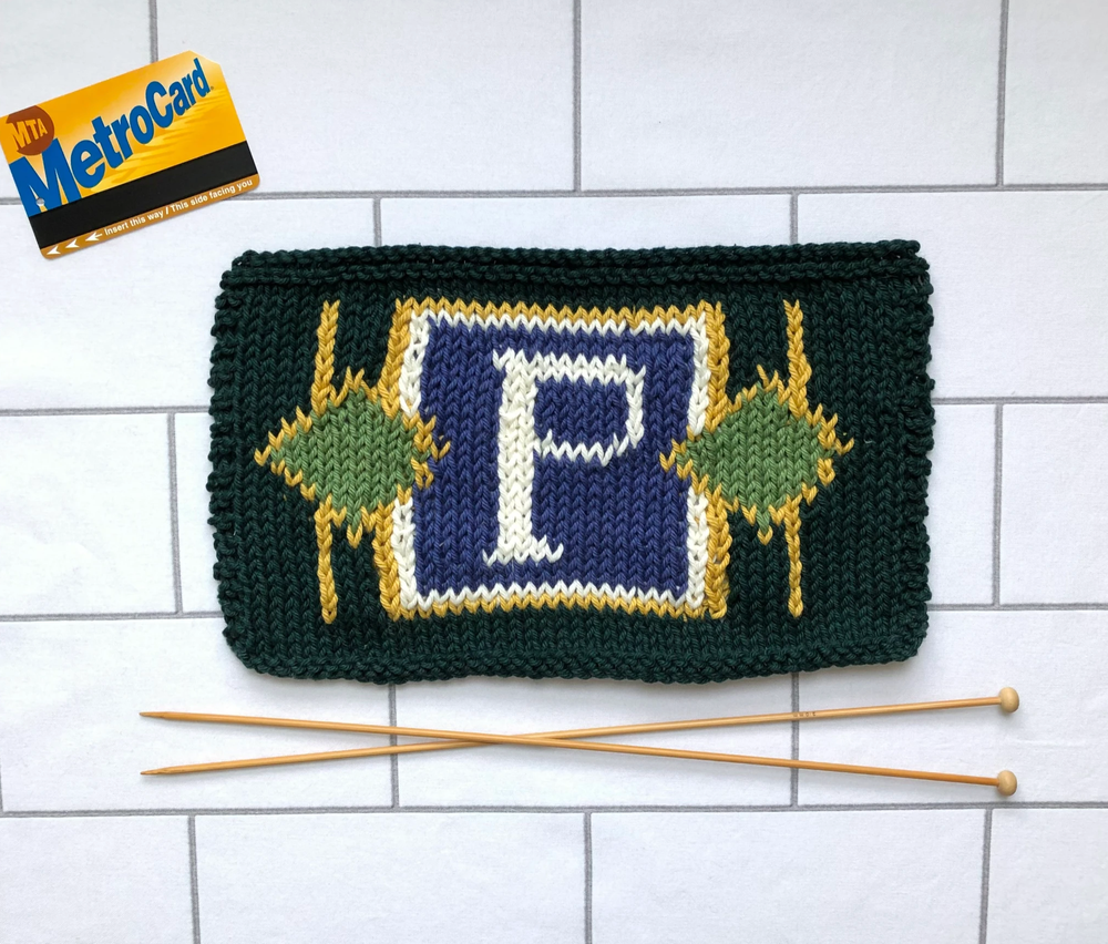 A metrocard, a knit version of the Prince Street subway mosaic and a pair of knitting needles
