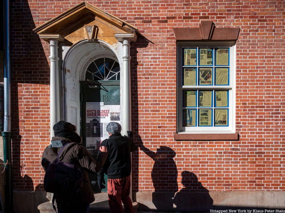 Two men stand outside the door of 18 Bowery, the Edward Mooney house, a brick townhouse with a window