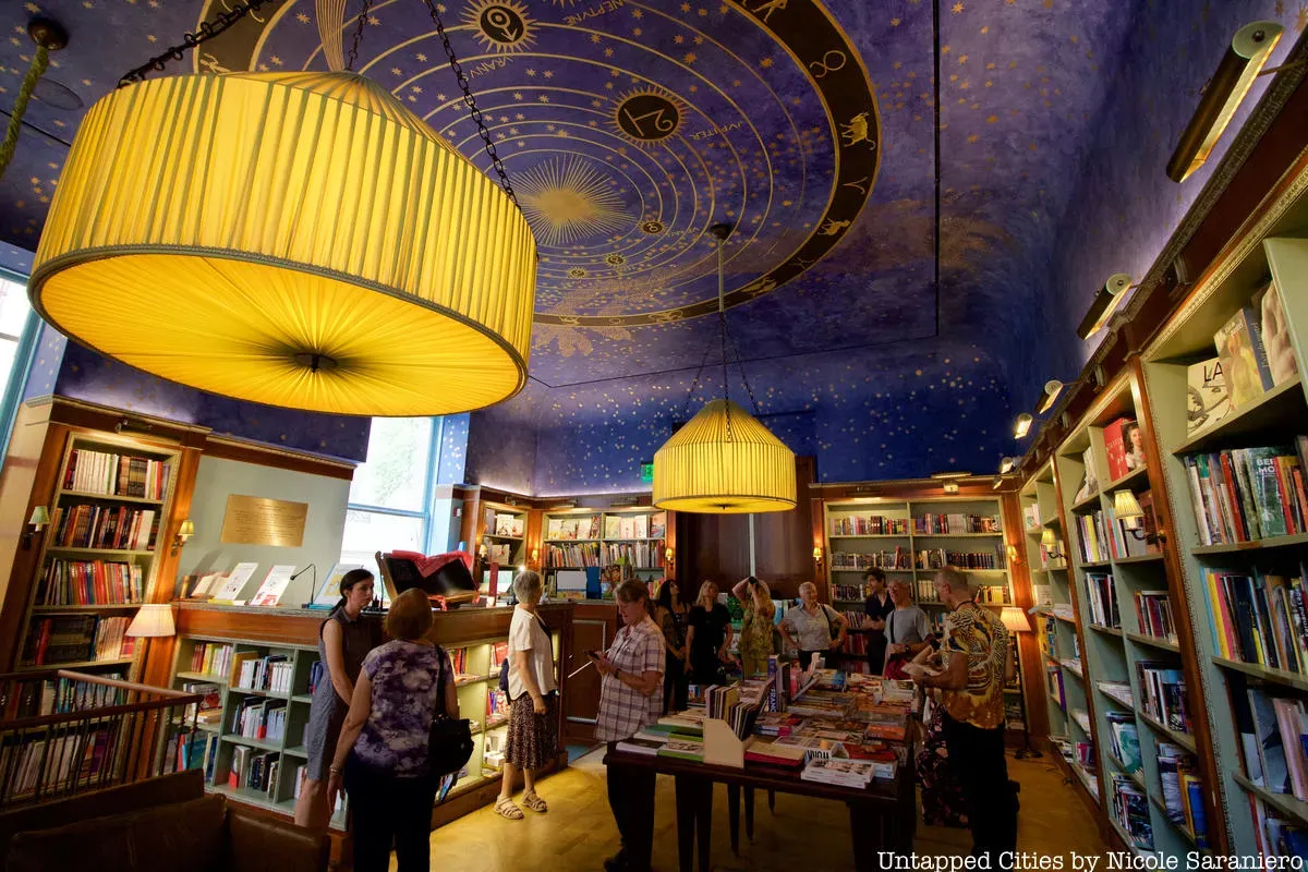 People browse a book store with a celestial painted ceiling