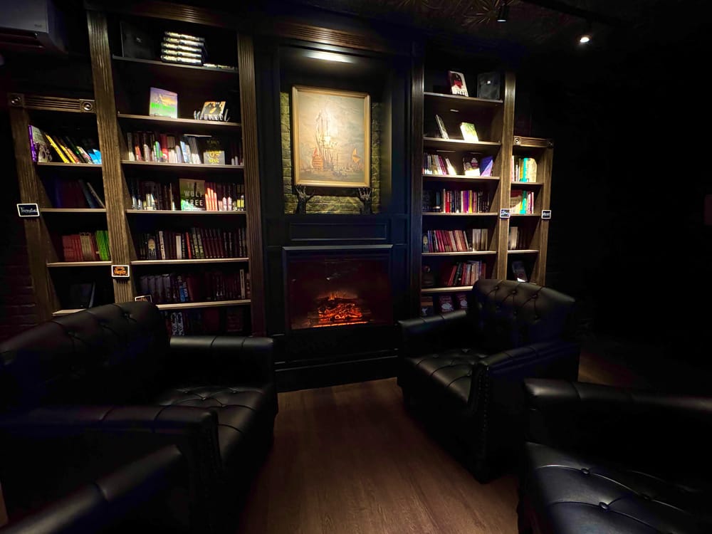 Interior of The Twisted Spine, bookshelves, a fireplace, and leather chairs
