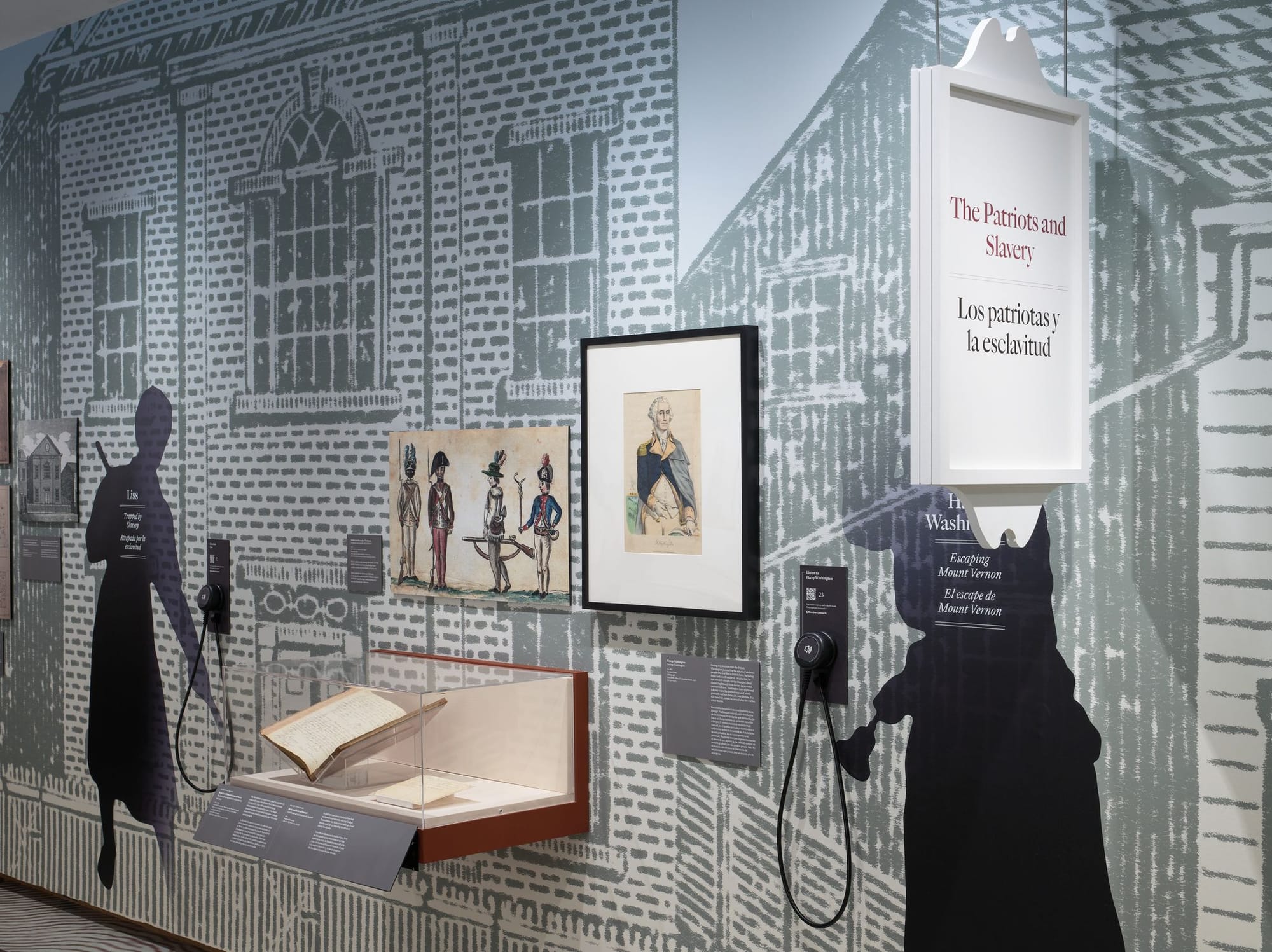 "The Patriots and Slavery" section of The Occupied City exhibit, featuring silhouette cutouts of enslaved individuals, framed historical illustrations of soldiers, a portrait of George Washington, and an open manuscript in a glass case, set against a large architectural mural.