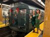 Two women standing on a subway platform next to the NYC Holiday Nostalgia Train