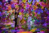 Two women stand amongst digital flowers at Artechouse NYC