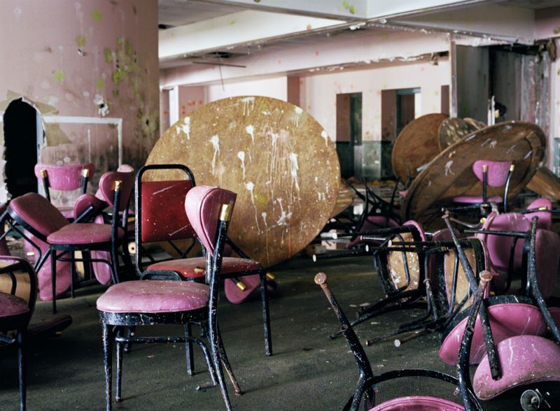 Pink chairs and round wooden tables splattered with paint in the Borscht Belt