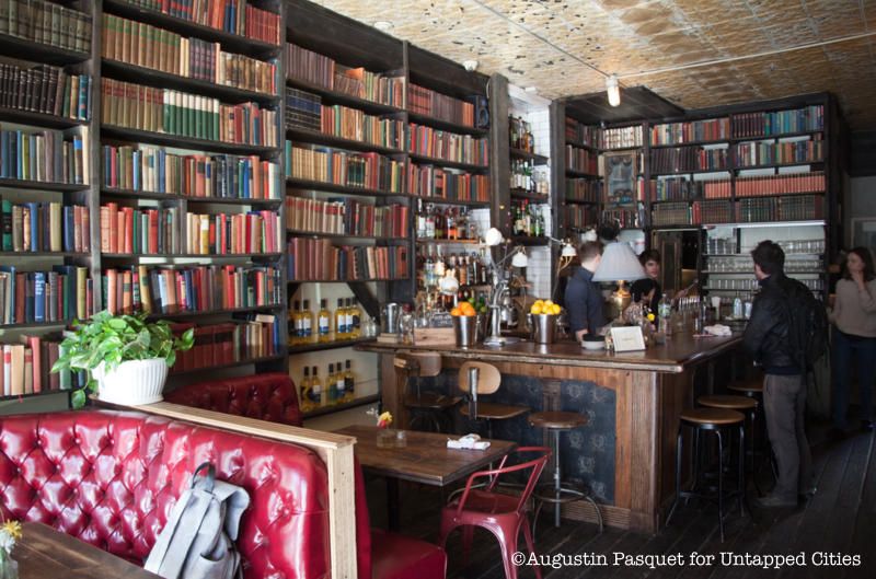 The booklined walls and red tufted booths at the cozy coffee show Milk and Roses in Greenpoint