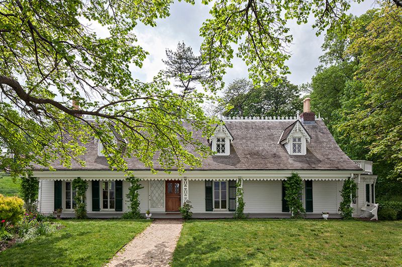 Bright green trees surround the front of the Alice Austen House in Staten Island
