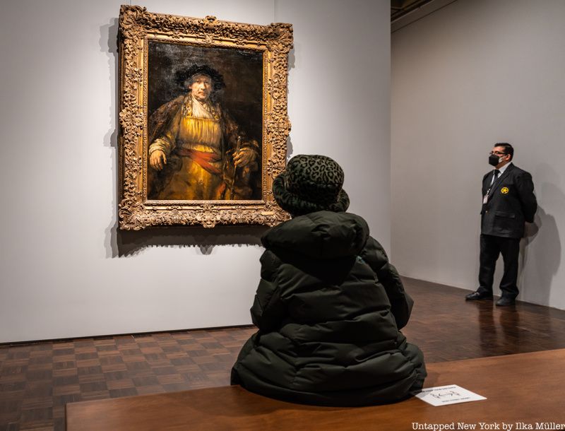 Woman on bench looking at Rembrandt painting at Frick Madison