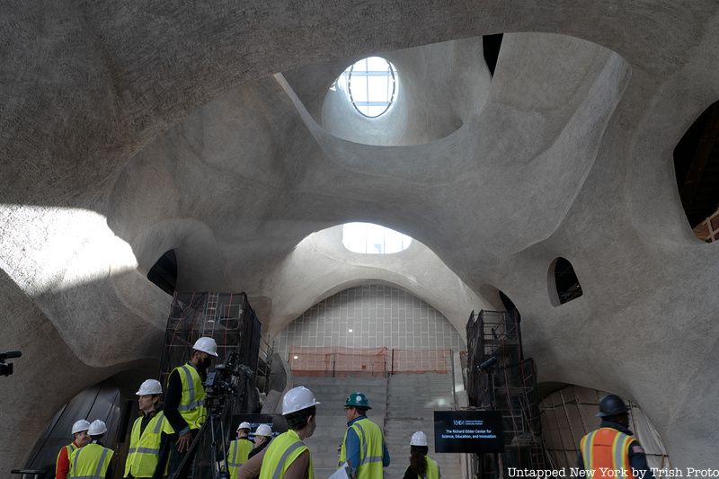 People in hardhats and yellow vets admire the construction of the Gilder Center atrium