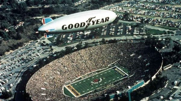 Goodyear Blimp flying over a packed football stadium at sunset