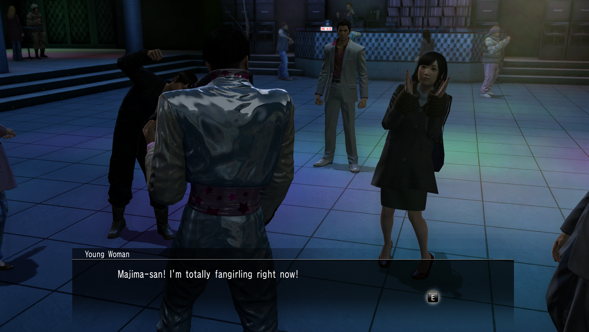 A screenshot from Yakuza Kiwami on the dancefloor; Kiryu and a fangirl of Majima are looking at the latter. The text reads: "Majima-san! I'm totally fangirling right now!"