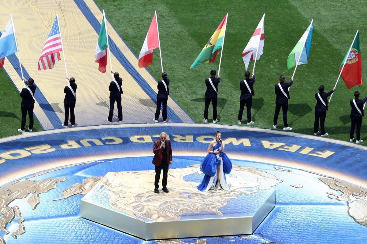 An image from the World Cup opening ceremony, featuring Andrea Bocelli, EJAE, and several people holding flags