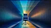 An empty dark blue leather executive chair sits centered in a symmetrical tunnel of blue-to-amber light, a conceptual image of an open seat of board leadership.