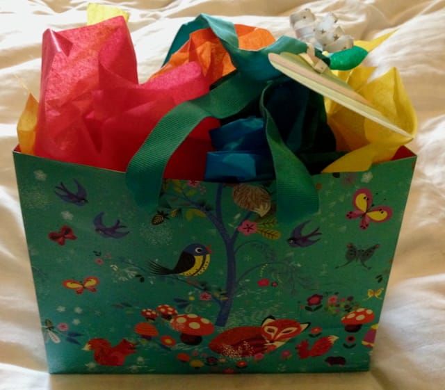 A gift bag with animals and insects around a tree
