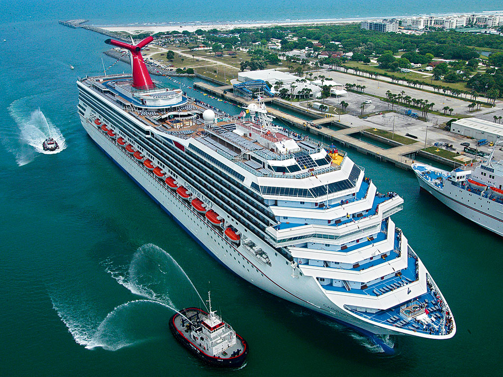 Carnival Cruise Line ship arriving at port with tugboats