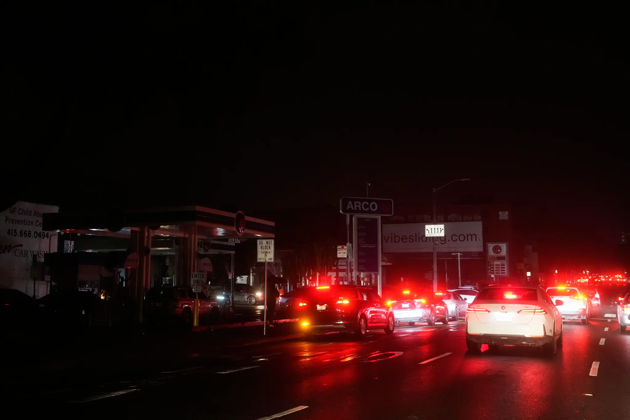 Long lines of cars on a San Francisco street during a nighttime power outage.