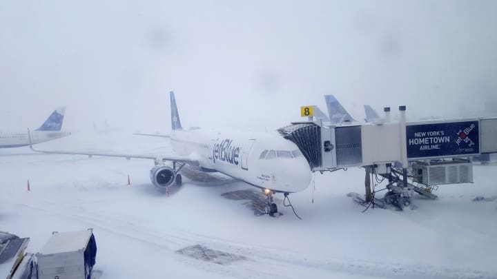 Snow-covered runways and grounded aircraft at JFK Airport during a winter storm.