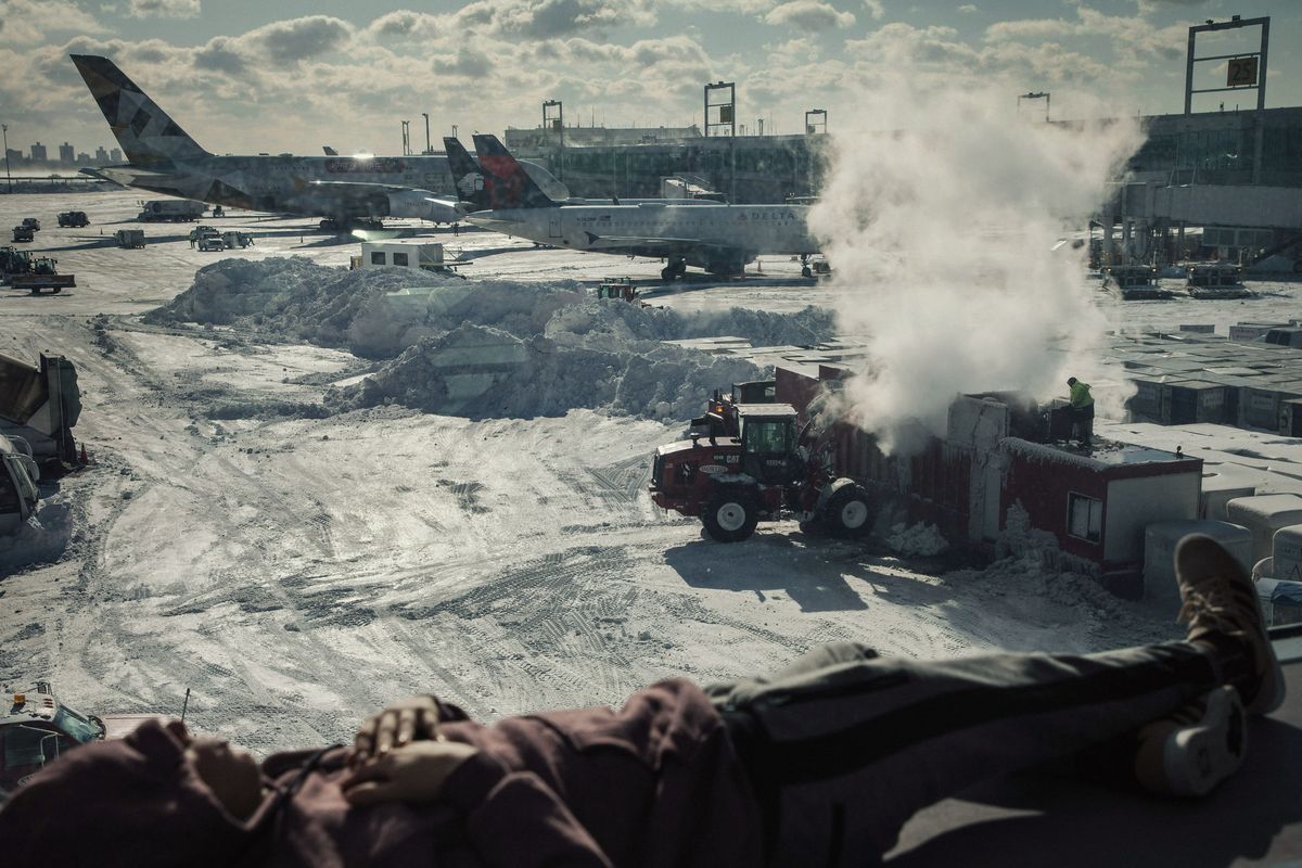 Snow-covered runways and grounded planes at JFK Airport during winter storm flight cancellations.