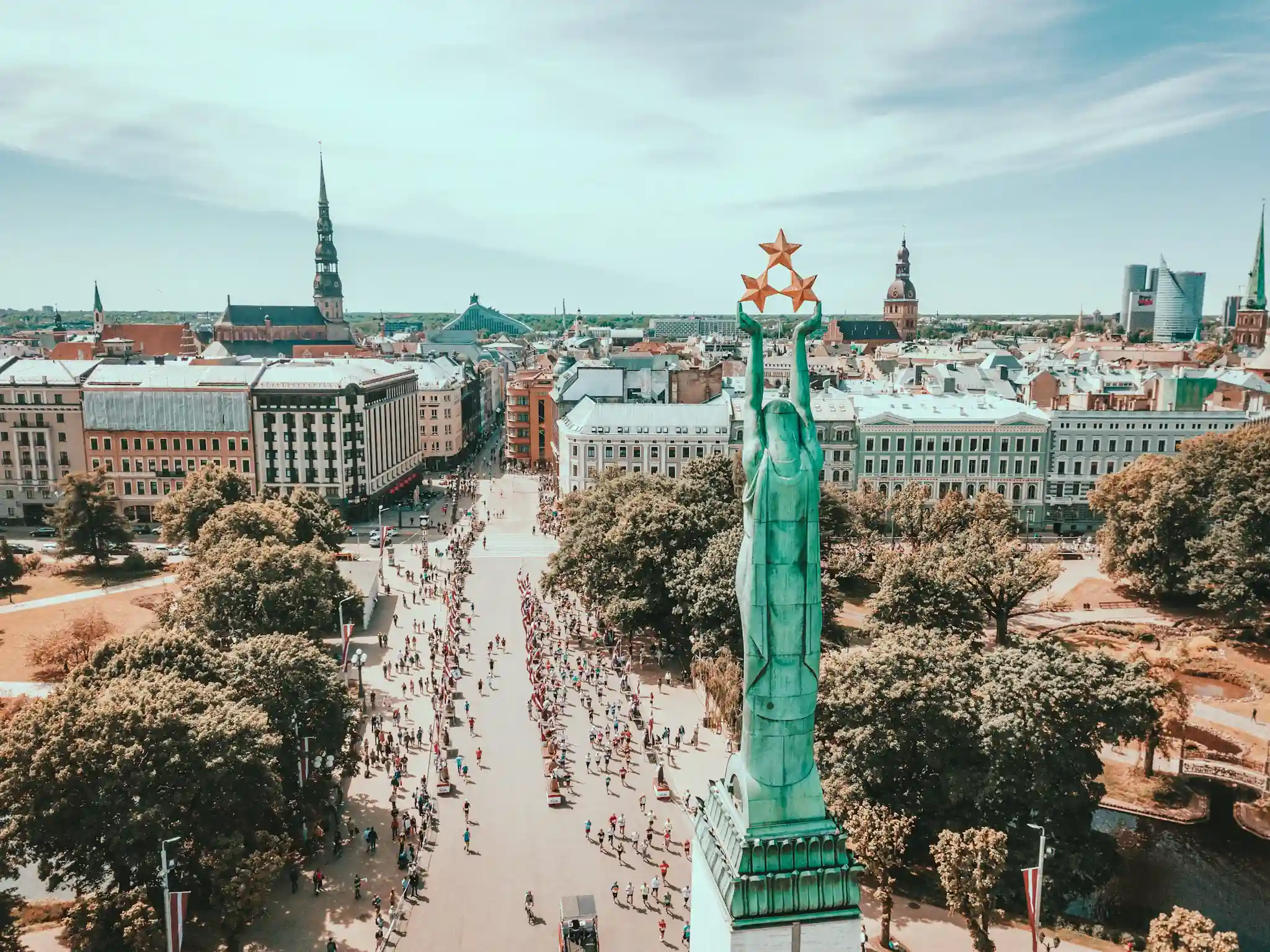 Aerial view of the Statue of Liberty in Riga with marathon runners in the background.
