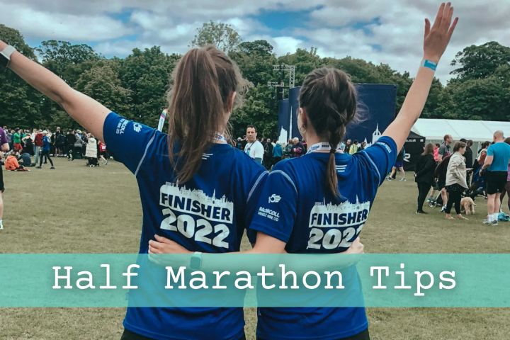 Two girls with their backs to the camera, arms in the air, and celebrating completing Edinburgh half marathon.