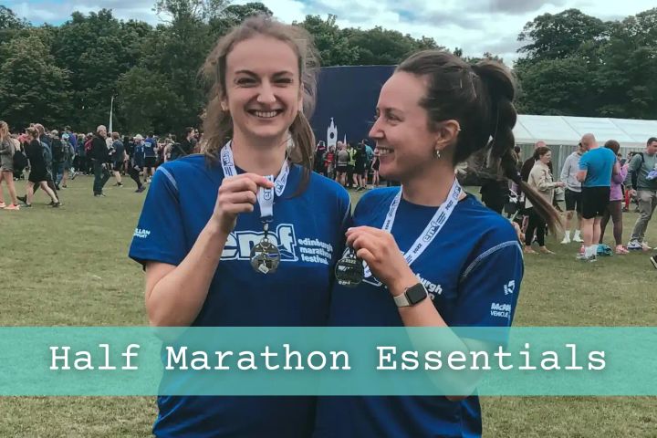 Two girls smiling after having completed the Edinburgh half-marathon, holding their medals.