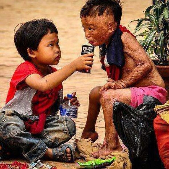 Young Child Helping Another With Drinking 