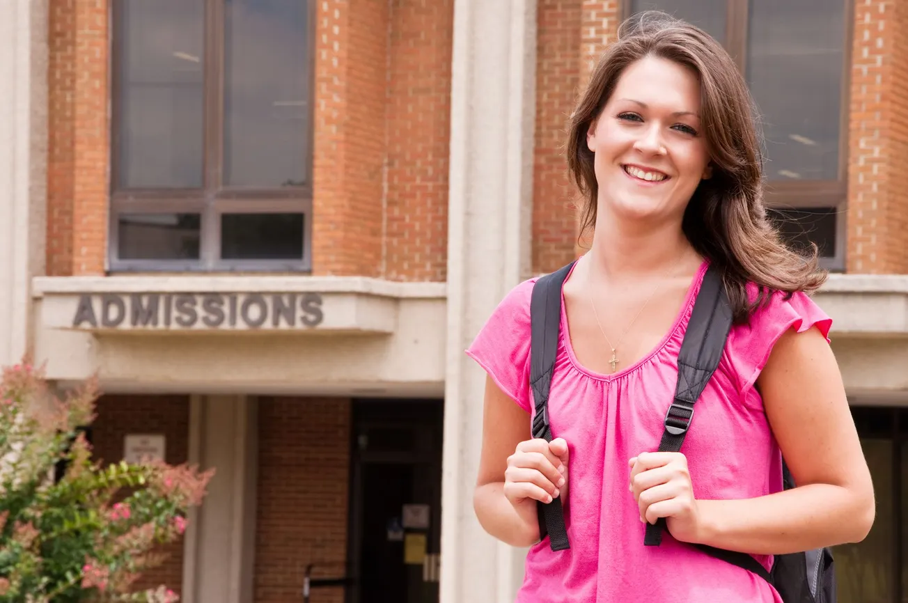 Younger student waiting outside of a college admissions building