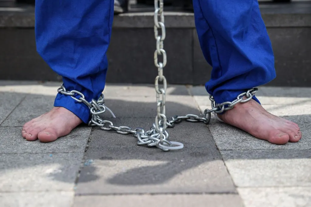 Demonstrators with chains on their hands and feet hold a protest as part of the worldwide "Stop Genocide Now" campaign